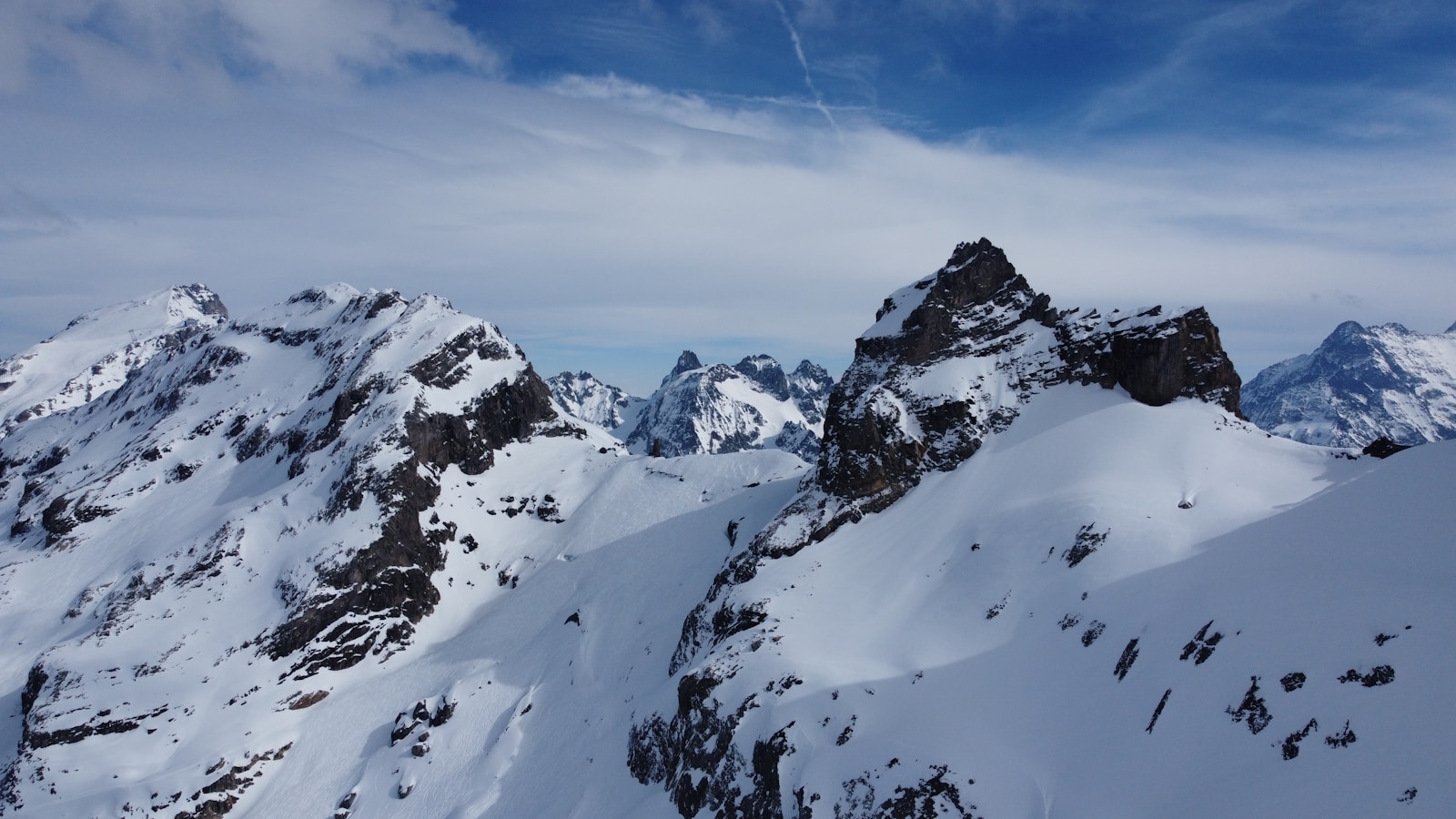 a mountain range covered in snow under a blue sky